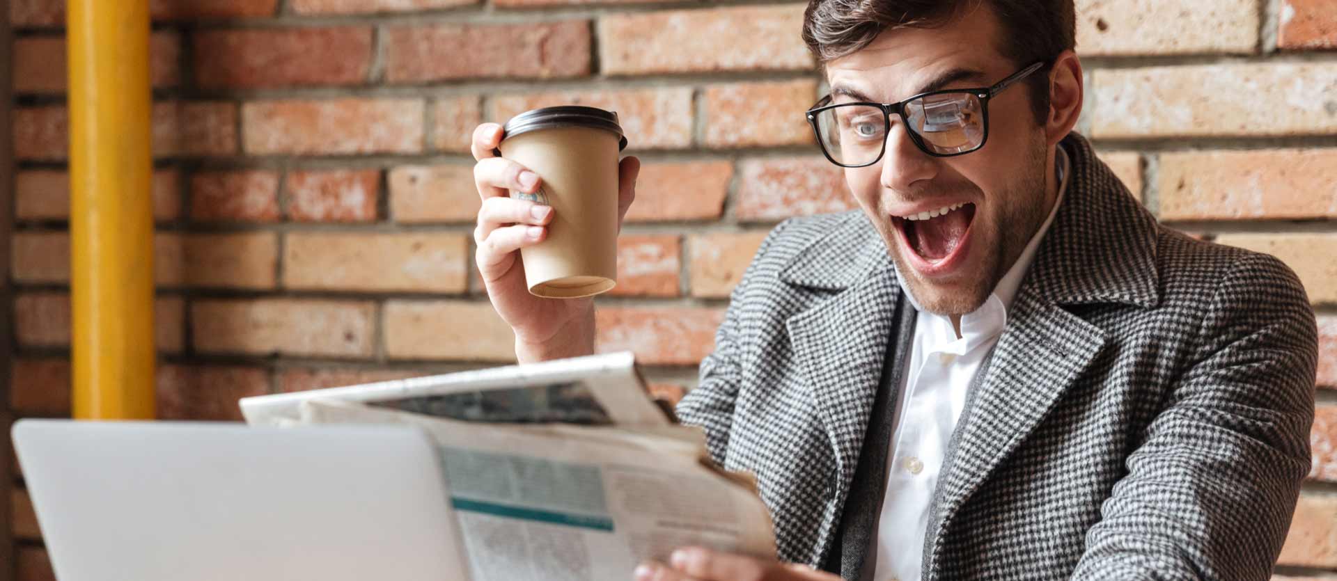Happy screaming business man in eyeglasses sitting by the table